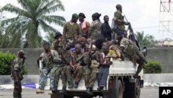 Soldiers loyal to Alassane Ouattara, along with several men who were detained for unknown reasons, drive past a checkpoint serving as an operating base, at one of the main entrances to Abidjan, Ivory Coast, April 7, 2011.