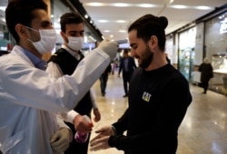 A man has his temperature checked and his hands disinfected as he enters the Palladium Shopping Center, in northern Tehran, Iran, March 3, 2020.