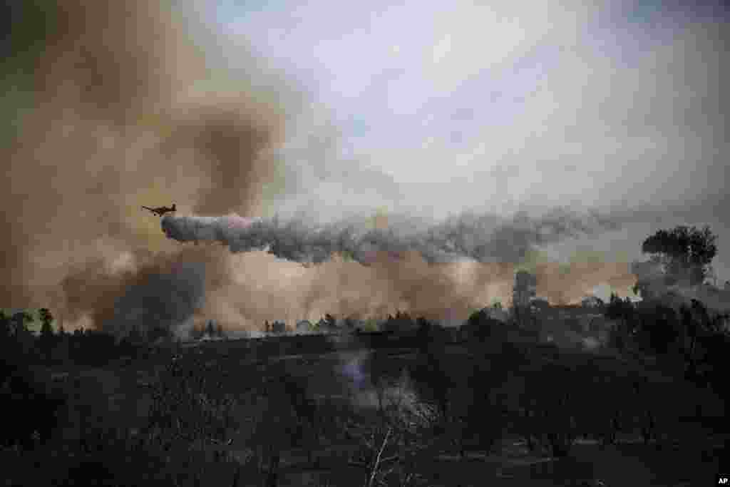 A firefighting plane passes over a fire started by a balloon with attached burning cloth launched by Palestinians from Gaza Strip in Karmia nature reserve park near the Israel and Gaza border.