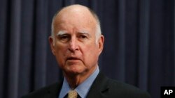 California Gov. Jerry Brown stands next to the podium before signing a budget bill, June 27, 2018, in Los Angeles. Brown granted pardons to 36 people in the past week, including three facing deportation to Cambodia.