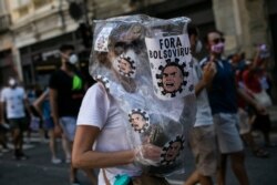 A woman wearing a plastic bag decorated with images depicting President Jair Bolsonaro as a virus, takes part in a protest against the government's response in combating COVID-19, May 29, 2021.