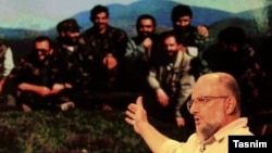Iranian controversial conservative activist Saeed Ghasemi during an Interview with a photo in background showing him and his comrades during the Bosnian conflict in the early 1990s.