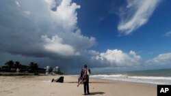 Rafiyya Farooq berdiri di pinggir pantai sementara awan badai bergerak ke daratan di Pantai Vero, Florida, Sabtu, 31 Agustus 2019. (Foto: AP)