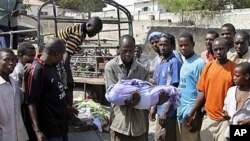 Somali man carries body of one-year-old child who was killed by errant al Shabab mortar targeting presidential palace, Mogadishu, March 19, 2012.