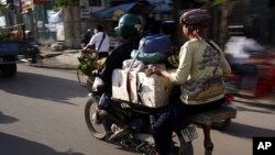 អ្នក​បើកម៉ូតូឌុបម្នាក់ដឹក​អ្នក​លក់ទំនិញ​ដែល​អង្គុយ​លើ​កែប​ពន្លាតទៅកាន់ផ្សារមួយ​ក្នុង​ក្រុង​ភ្នំពេញ ថ្ងៃទី២៣ កក្កដា ២០១១។