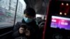 A passenger wearing a face mask checks his mobile phone on a bus, following an outbreak of the novel coronavirus in the country, in Beijing, China, Feb. 21, 2020. 