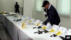 FILE - A Central Bureau of Judicial Investigation official gestures toward confiscated weapons with a commando in the background in Sale, Morocco, Sept. 14, 2015. Moroccan officials announced the dismantling of a cell in Essaouira that was in touch with Islamic State.