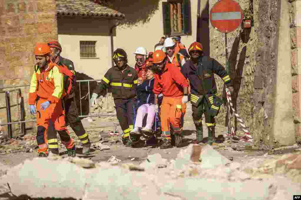 Bombeiros prestam socorro a mulher em cadeira de rodas&nbsp; depois de um terramoto de intensidade 6,6 em Norcia, na Itália.