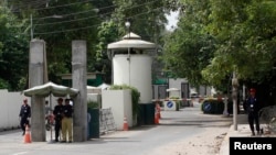 FILE - A policeman (2nd R) and private security personnel stand guard at the entrance of a road leading towards the U.S. consulate in Lahore, Pakistan.