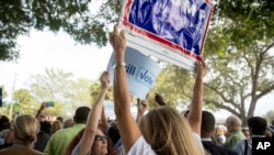 A supporter of Democratic presidential candidate Hillary Clinton attempts to block a Republican presidential candidate Donald Trump supporter from waving a sign as Clinton greets supporters outside an early voting station at the Pompano Beach Amphitheater