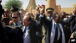 French President Francois Hollande holds hands with Mali's interim President Dioncounda Traoré in Timbuktu, Mali, February 2, 2013.