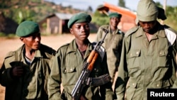 A child soldier (C), known as "Kadogo," meaning "small one" in Swahili, stands at the front line at Kanyabayonga in eastern Congo, November 17, 2008. Snatched from their homes by armed men who force them to carry ammunition, fight and kill, beaten if they