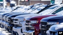 FILE - Several 2021 Silverado pickup trucks sit at a Chevrolet dealership in Englewood, Colorado, Feb. 21, 2021.