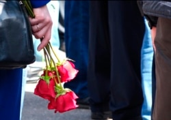 In this grab taken from footage by the Russian State Atomic Energy Corporation ROSATOM press service, a woman holds roses as people gather for the funerals of five Russian nuclear engineers killed by a rocket explosion in Sarov, Aug. 12, 2019.