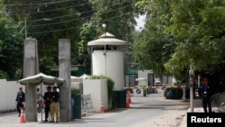 FILE - A policeman (2nd R) and private security personnel stand guard at the entrance of a road leading towards the U.S. consulate in Lahore.