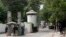 FILE - A policeman (2nd R) and private security personnel stand guard at the entrance of a road leading towards the U.S. consulate in Lahore.