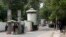 FILE - A policeman (2nd R) and private security personnel stand guard at the entrance of a road leading towards the U.S. consulate in Lahore, Pakistan.
