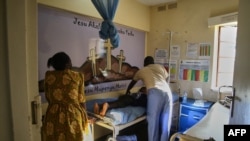 FILE — A mother watches as a health worker tends to her son recuperating in the paediatric ward at Karanda Mission Hospital in Mount Darwin on March 2, 2024.