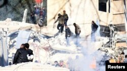 People inspect the damage at the site of a strike in the Mazzeh neighborhood of Damascus