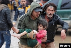Un hombre carga a una niña en el poblad sirio de Jandaris después de un terremoto de magnitud 7,8 que azotó esa comunidad el 6 de febrero de 2023.