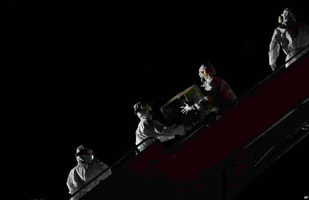 Venezuelan workers wearing protective face masks and suits unload boxes of humanitarian aid as medical supplies and specialists from China arrive to Simon Bolivar International Airport in La Guaira.