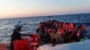 Seorang anggota kelompok LSM "Sea-Watch" memberikan jaket pelampung kepada para migran Afrika yang berdesakan menaiki kapal karet di lepas pantai Libya di Laut Tengah, 23 Juli 2022. 