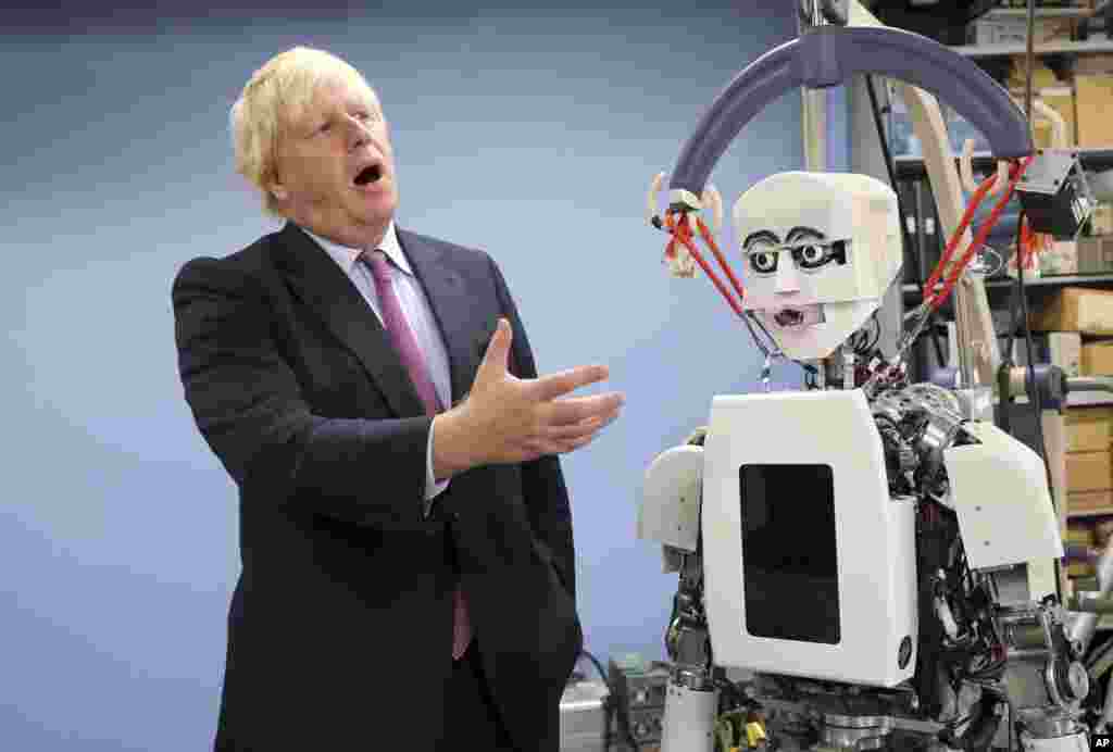 Britain's Foreign Secretary Boris Johnson gestures as he looks at a humanoid robot at Research Institute for Science and Engineering at Waseda University's campus in Tokyo.