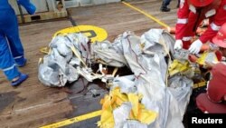 Pekerja PT Pertamina Persero di kapal Prabu milik Pertamina, memeriksa barang-barang yang diyakini dari pesawat Lion Air JT610 yang jatuh, di lepas pantai Kabupaten Karawang, Jawa Barat, 29 Oktober 2018. (Foto: Antara/PT Pertamina via Reuters)