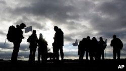 Demonstrators with white flags silhouette against a cloudy sky as they wait for the launch of the Civil March for Aleppo at Tempelhof former airport in Berlin, Dec. 26, 2016.