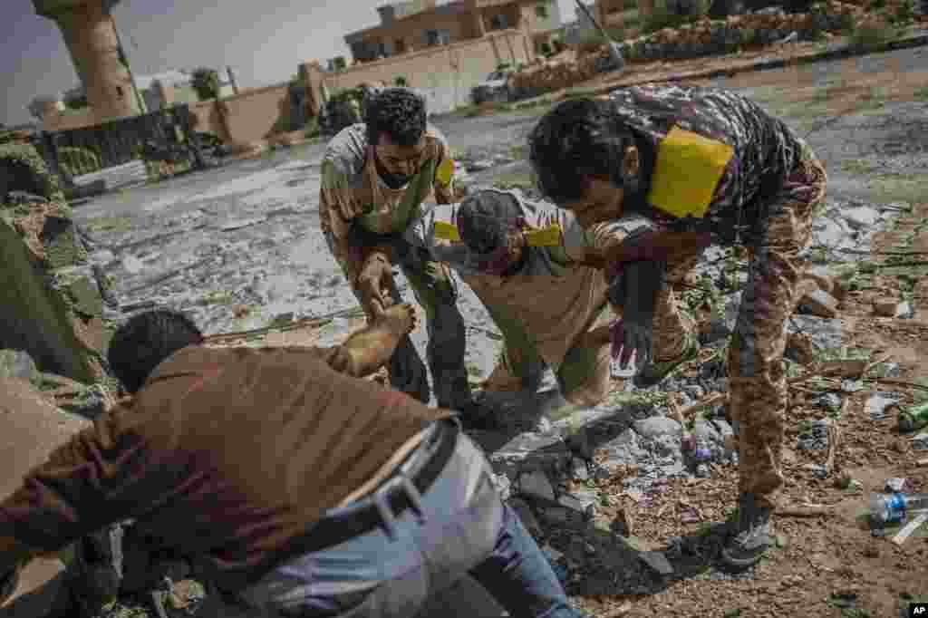 A fighter for the Libyan forces affiliated with the Tripoli government is helped by comrades after being shot by a sniper, in Sirte, Oct. 2, 2016.