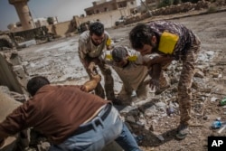 FILE - A fighter of the Libyan forces affiliated to the Tripoli government is helped by comrades after being shot by a sniper, in Sirte, Libya, Oct. 2, 2016.