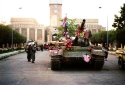 FILE - Tanks manned by Taliban fighters and decorated with flowers are seen in front of the the damaged Presidential palace in Kabul, Afghanistan, Sept. 28, 1996.