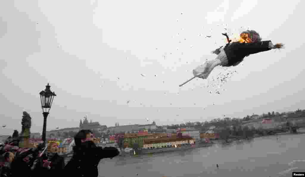 A man throws a burning effigy depicting outgoing Czech President Vaclav Klaus from the medieval Charles Bridge during a celebration rally for the end of Klaus&#39; presidency in Prague. 