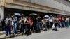 FILE - People queue up to try to buy basic food items outside a supermarket in Caracas, Venezuela, April 28, 2016. 