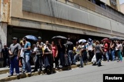 People queue to try to buy basic food items outside a supermarket in Caracas, Venezuela, April 28, 2016.