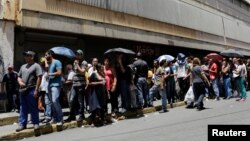 FILE - People line up to try to buy basic food items outside a supermarket in Caracas, Venezuela, April 28, 2016. 