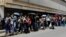 FILE - People queue up to try to buy basic food items outside a supermarket in Caracas, Venezuela, April 28, 2016. 