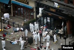 Officials take crime scene photos a day after two explosions hit the Boston Marathon in Boston, Massachusetts, April 16, 2013.