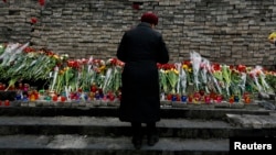 FILE - A woman mourns before a memorial to those killed in violence in Kyiv, Feb. 25, 2014 — the day that parliament voted to send fugitive President Viktor Yanukovich to be tried by the International Criminal Court for "serious crimes."