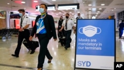 FILE -A flight crew walk through the terminal at Sydney Airport, Nov. 29, 2021.
