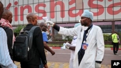 FILE - A health worker checks people's temperatures as they disembark a plane at the airport in Kinshasa, Congo, June 2, 2018.