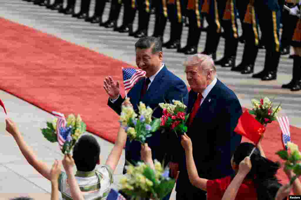 在北京人民大会堂东门外广场举行的欢迎仪式上，美国总统特朗普和中国国家主席习近平向挥舞鲜花和美中小国旗的中国儿童微笑致意。(2026年5月14日)