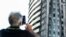 A man takes a picture as firefighters work on the blackened ruins of a block of flats after a fire ripped through the building, in Milan, Italy, Aug. 30, 2021. 
