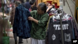 A woman checks a jacket for sale at an open market along a Hutong alley in Beijing, China, September 9, 2012. 