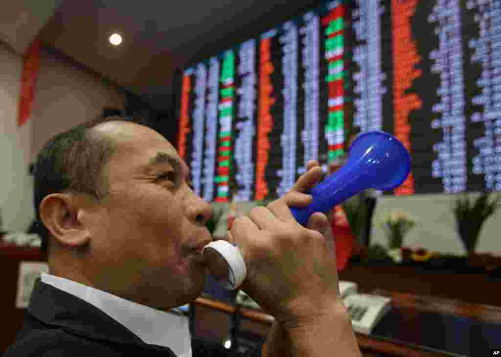 A Filipino trader blows a horn in front of the electronic board during the last day of trading this year at the Philippine Stock Exchange in the financial district of Makati, south of Manila. The Exchange index rose to a record high of 7,403.65.