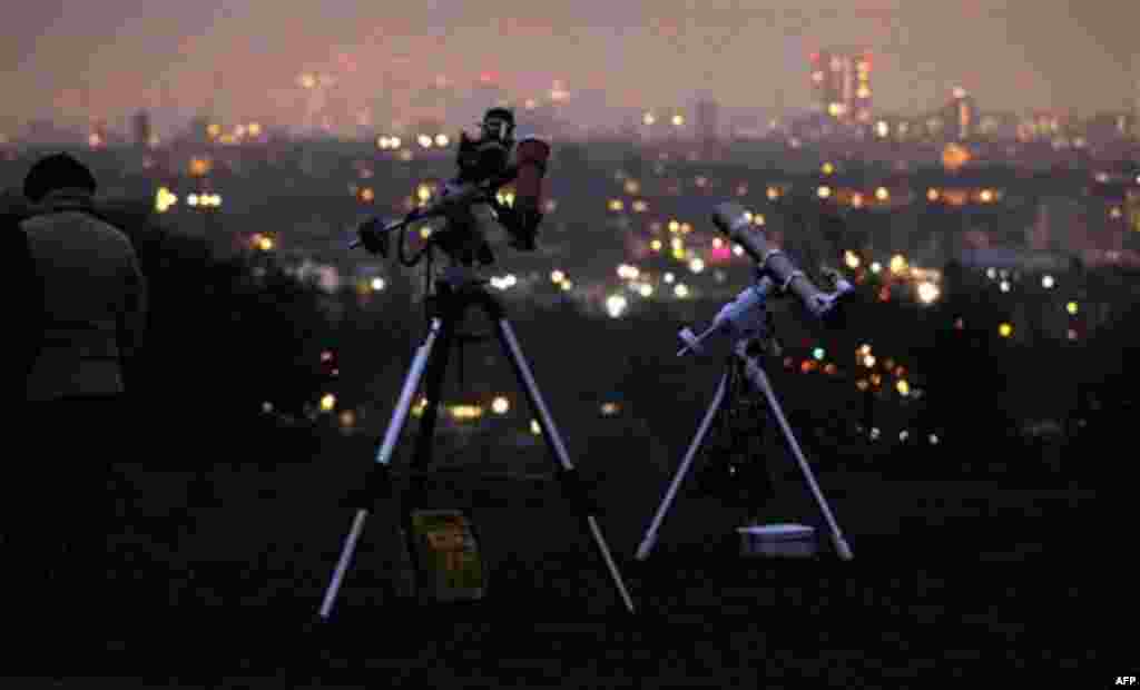 Telescopes setup up to view the partial solar eclipse are seen backdropped by central London, from Parliament Hill on Hampstead Heath in London, early Tuesday, Jan. 4, 2011. Cloudy skies hung over London on Tuesday morning, preventing a view from Parliam