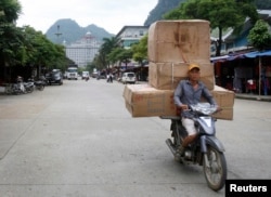 FILE - A man transports boxes of Chinese goods at Tan Thanh market, on the border with China, in Vietnam's northern Lang Son province, July 30, 2014.