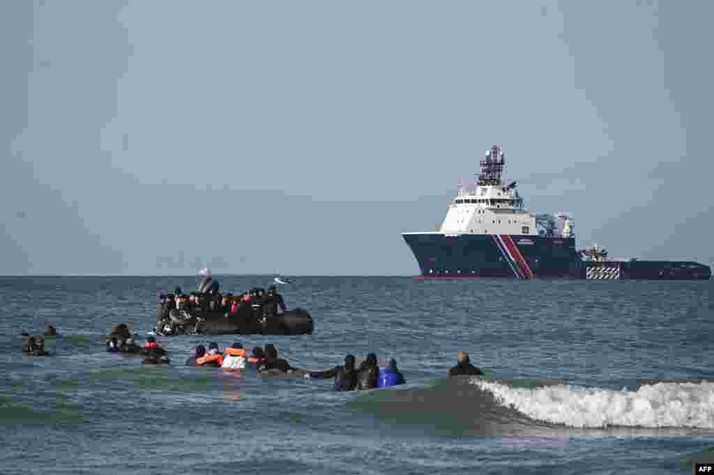 Para migran berenang untuk menaiki perahu penyelundup guna mencoba menyeberangi Selat Inggris di lepas pantai Audresselles, Prancis utara. (AFP)&nbsp;