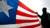 FILE - A Liberian refugee holds a Liberian flag.