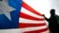 FILE - A Liberian refugee holds a Liberian flag.